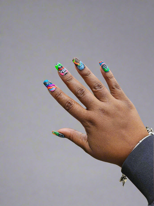 Hand with colorful nail polish against a grassy background